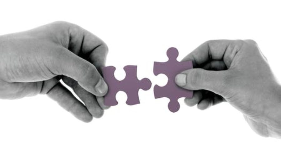 Two hands pushing puzzle pieces together